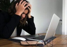 woman at desk facing burnout, PhD proposal sample writing